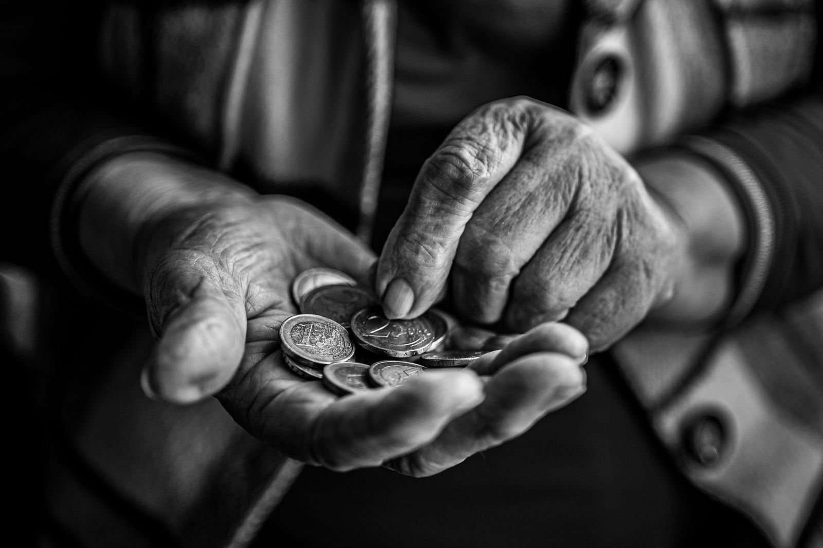 Mains d'une personne âgée comptant des pièces de monnaie